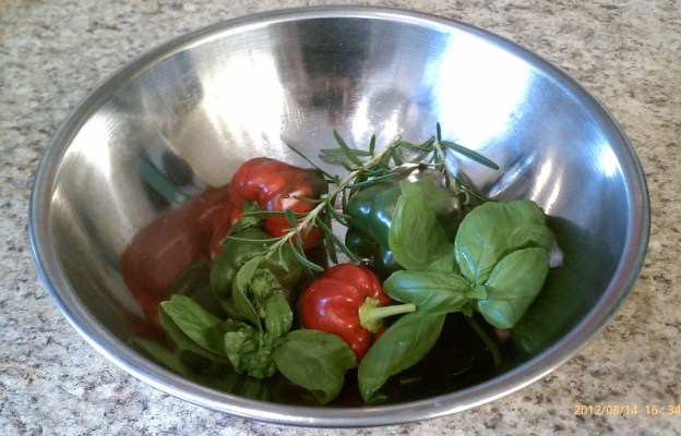 a bowl with homegrown tomatoes peppers, rosemary, and basil